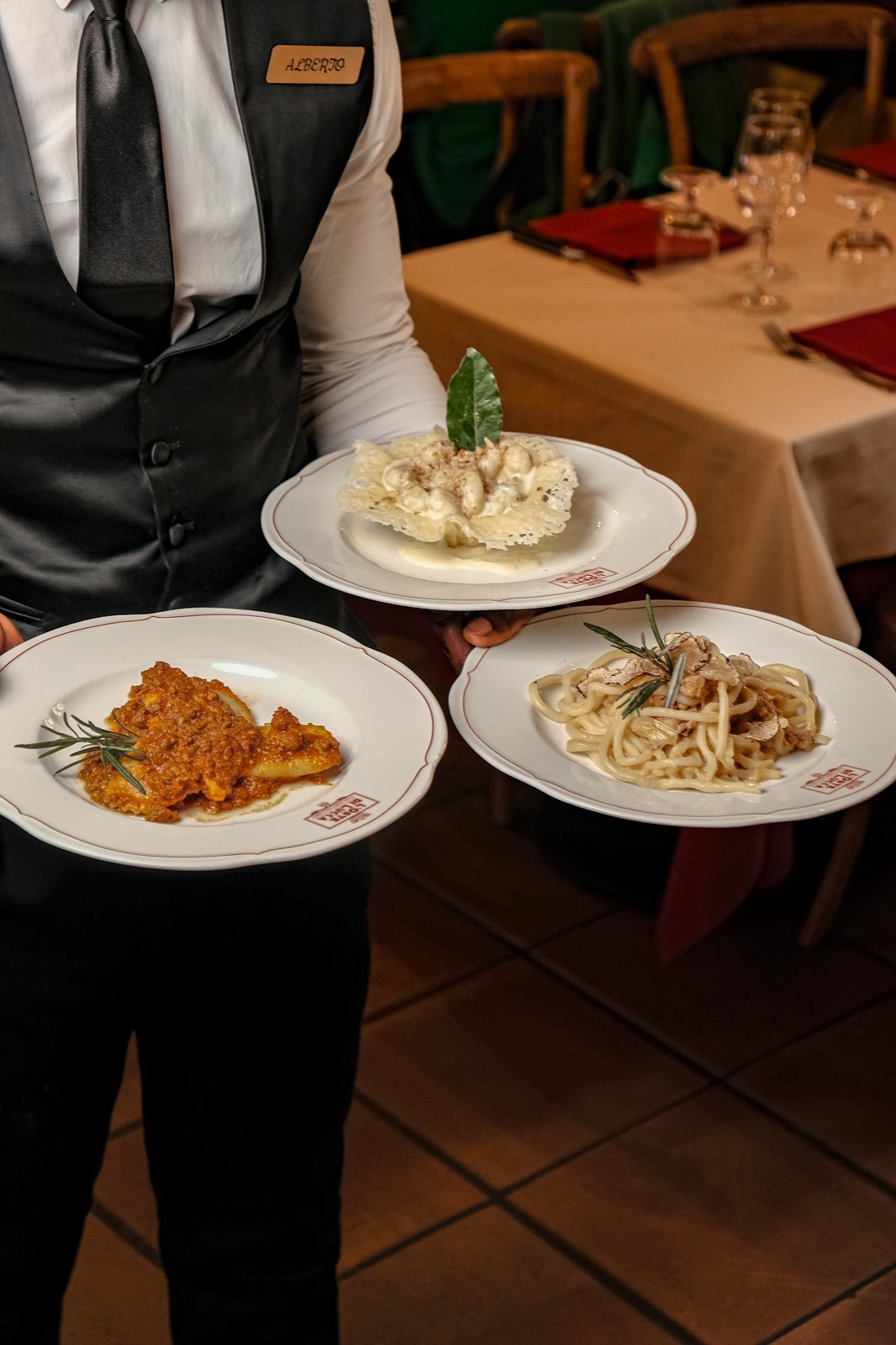 A waiter of L&rsquo;Oste di Lucca carrying dishes into the dining room
